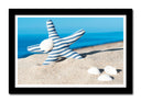 Cuadro enmarcado negro estrella de mar con rayas azul y blanca sobre la playa, arena